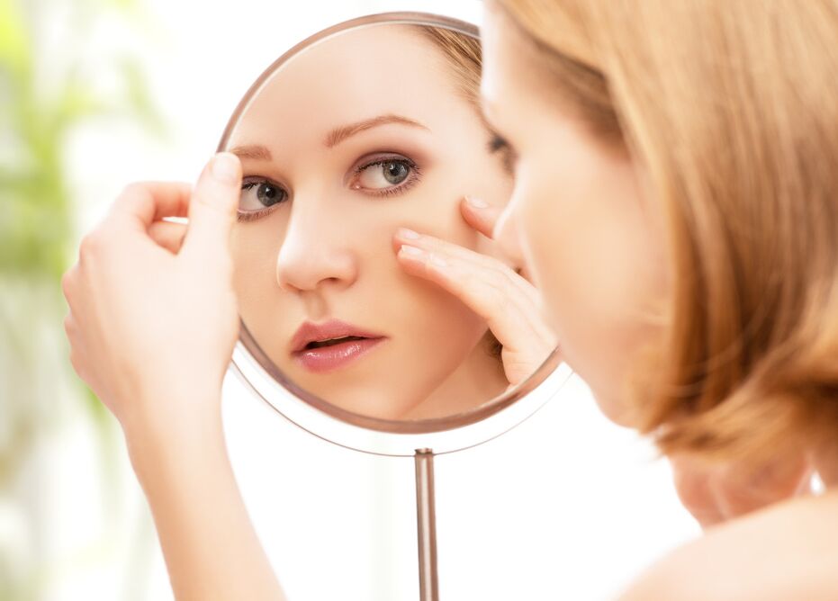 girl looks in the mirror after rejuvenating facial skin